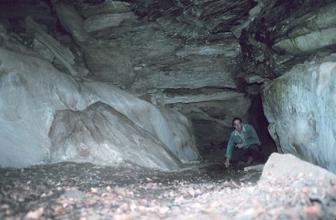 The inside of this, the largest Ice Cave, measures approximately 30 feet long, 10 feet wide, and 8 feet high. This cave is the space left between four or five blocks of sandstone. I am pointing to ice on the floor of the cave. Photograph taken near the entrance